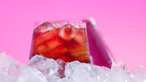Nahaufnahme-Eines-Gekühlten-Kaltgetränks-Im-Glas,-Das-Aus-Der-Dose-Auf-Eiswürfel-Vor-Rosa-Hintergrund-Gegossen-Wurde-2